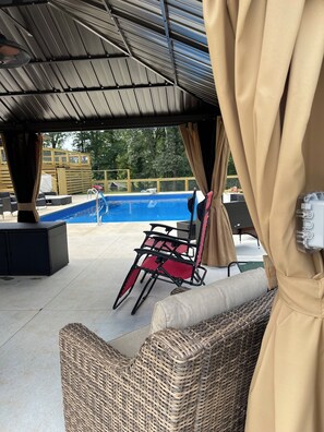 An outdoor patio area with a pool, wicker furniture, and a covered seating area. - Basement Apt near Athens,  Clemson, Lake Hartwell & Commerce-Shared Pool&Hot Tub (Canon)