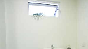 Een kleine badkamer met toilet, wastafel en een klein raam.