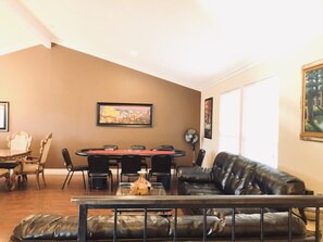 Un salon comprenant une table à manger, un canapé en cuir noir et un tableau accroché au mur.