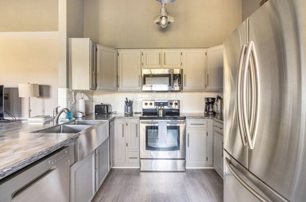 Enjoy cooking in this well-lit kitchen with a refrigerator, oven, microwave, sink, and ample storage.