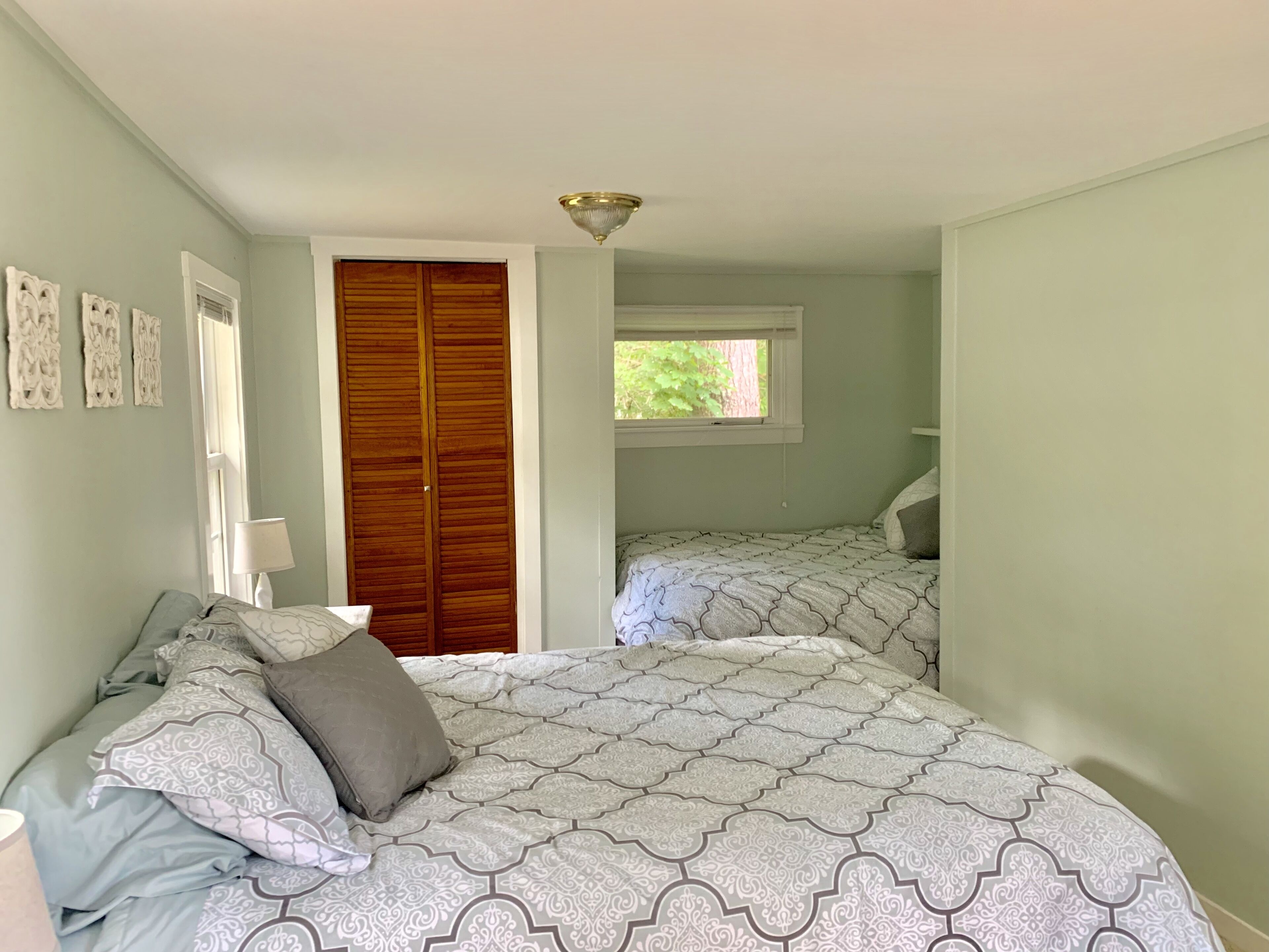 A bedroom with a bed, a wardrobe, a window, and a lamp.