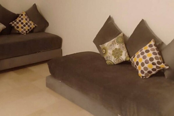 A living room with a sofa and two armchairs, each with patterned cushions.
