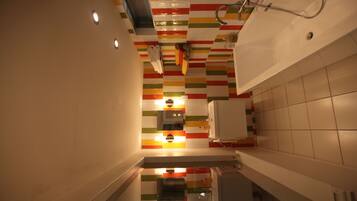 Une salle de bain moderne avec un mur décoré de rayures colorées, un espace douche et un lavabo avec un miroir.