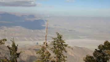 Eine gebirgige Landschaft mit vereinzelter Vegetation und weit entfernten Windkraftanlagen.