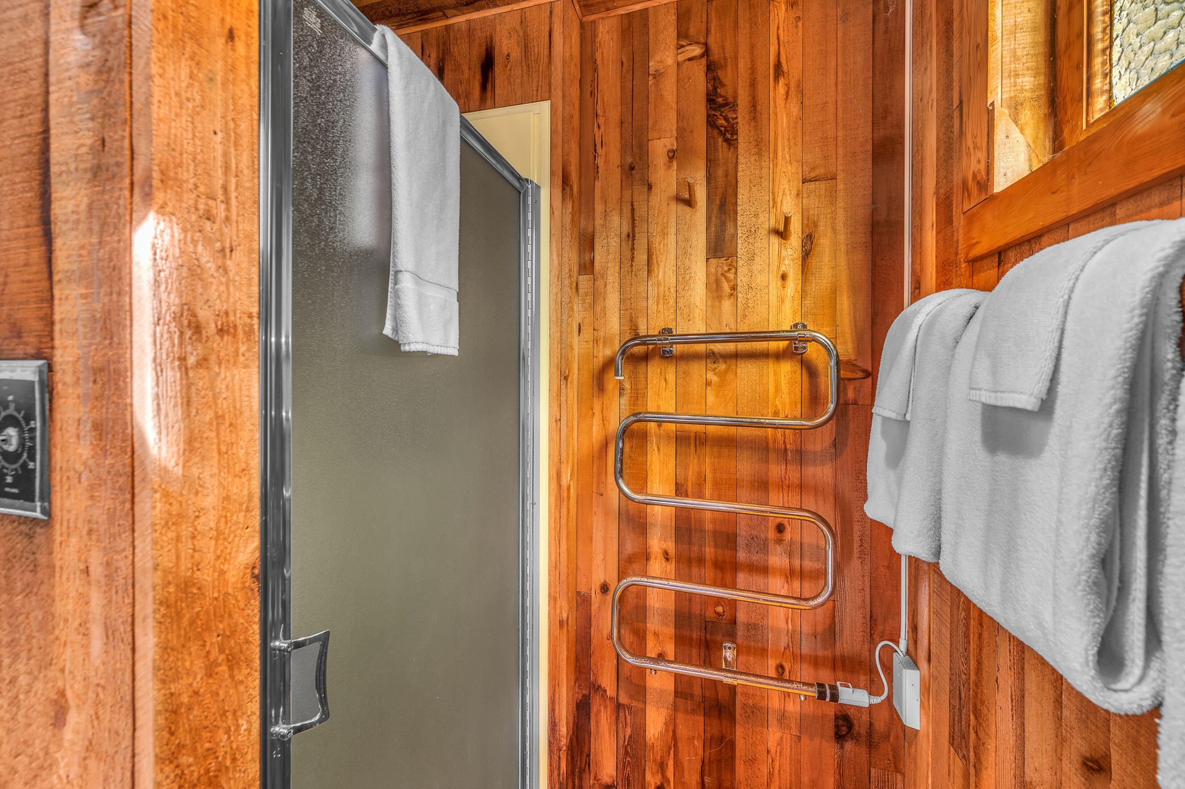Un intérieur en bois avec une douche, un porte-serviettes et une serviette à portée de main.