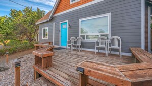 A house with a wooden deck, a blue door, and two white plastic chairs. - Pet-Friendly Cottage, Walk to Beach (Depoe Bay)