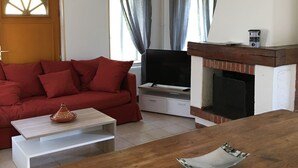 A living room with a red sofa, a wooden coffee table, a flat-screen TV, and a fireplace. - Domain House - Landin Castle (LE LANDIN)
