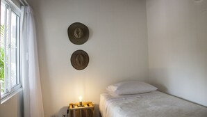 Un dormitorio con cama, una mesita de noche con lámpara y dos adornos en la pared.