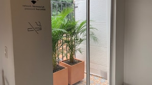 Una habitación con puerta de vidrio corredera que da a un espacio exterior con plantas en macetas.