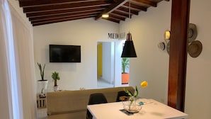 Una sala de estar moderna con un sofá, una mesa de comedor y un televisor montado en la pared.
