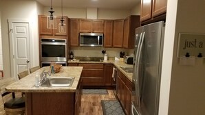 Una cocina moderna con armarios de madera, electrodomésticos de acero inoxidable y encimera de granito.