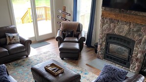 Una sala de estar con chimenea de piedra, sofás de cuero y un televisor.