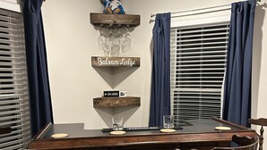 Una zona de bar con mostrador de madera, taburetes y un letrero que dice "Balsam Lodge".