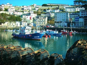 Un port où sont amarrés des bateaux de pêche, entouré d’une ville côtière avec ses bâtiments.