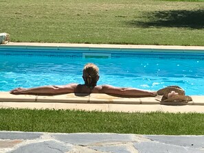 Une personne allongée sur le dos dans une piscine dont l’eau est d’un bleu limpide.
