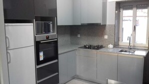 Eine Küche mit Kühlschrank, Mikrowelle, Backofen, Gasherd und einem Fenster mit Blick.