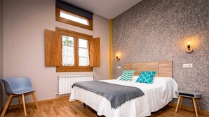 Une chambre à coucher comprenant un lit, une chaise, un radiateur et une fenêtre avec des volets en bois.