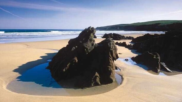 Une plage avec de gros rochers et une zone de sable.