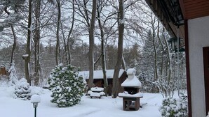 Un área exterior cubierta de nieve con una estructura de madera, posiblemente una cabaña, rodeada de árboles.