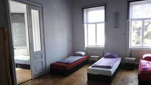 A room with three single beds, a wooden floor, and a door leading to another room. - Raisa Apartments PR4 (Pressbaum)