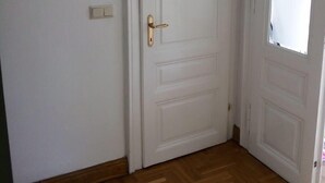 A white door with a brass handle, a small circular plaque above it, and a light switch to the left. - Raisa Apartments PR4 (Pressbaum)