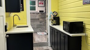 Una cocina compacta con encimera negra, microondas y cafetera.