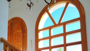 Una scala in legno con una ringhiera in marmo, un'ampia finestra ad arco e una porta in legno.