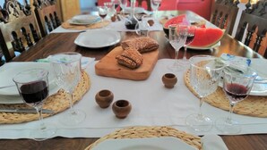 Un tavolo da pranzo apparecchiato con piatti, bicchieri, pane e una zucca anguria come elemento decorativo.