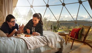Una pareja cenando en un salón en forma de cúpula geométrica con vistas al campo.