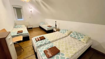 A room with two beds, a desk, a chair, a small table, and a window.