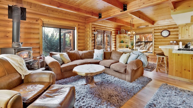 A cozy log cabin interior with a fireplace, leather sofas, a dining area, and a kitchen. - Knotty AND Nice #177 (Big Bear Lake)