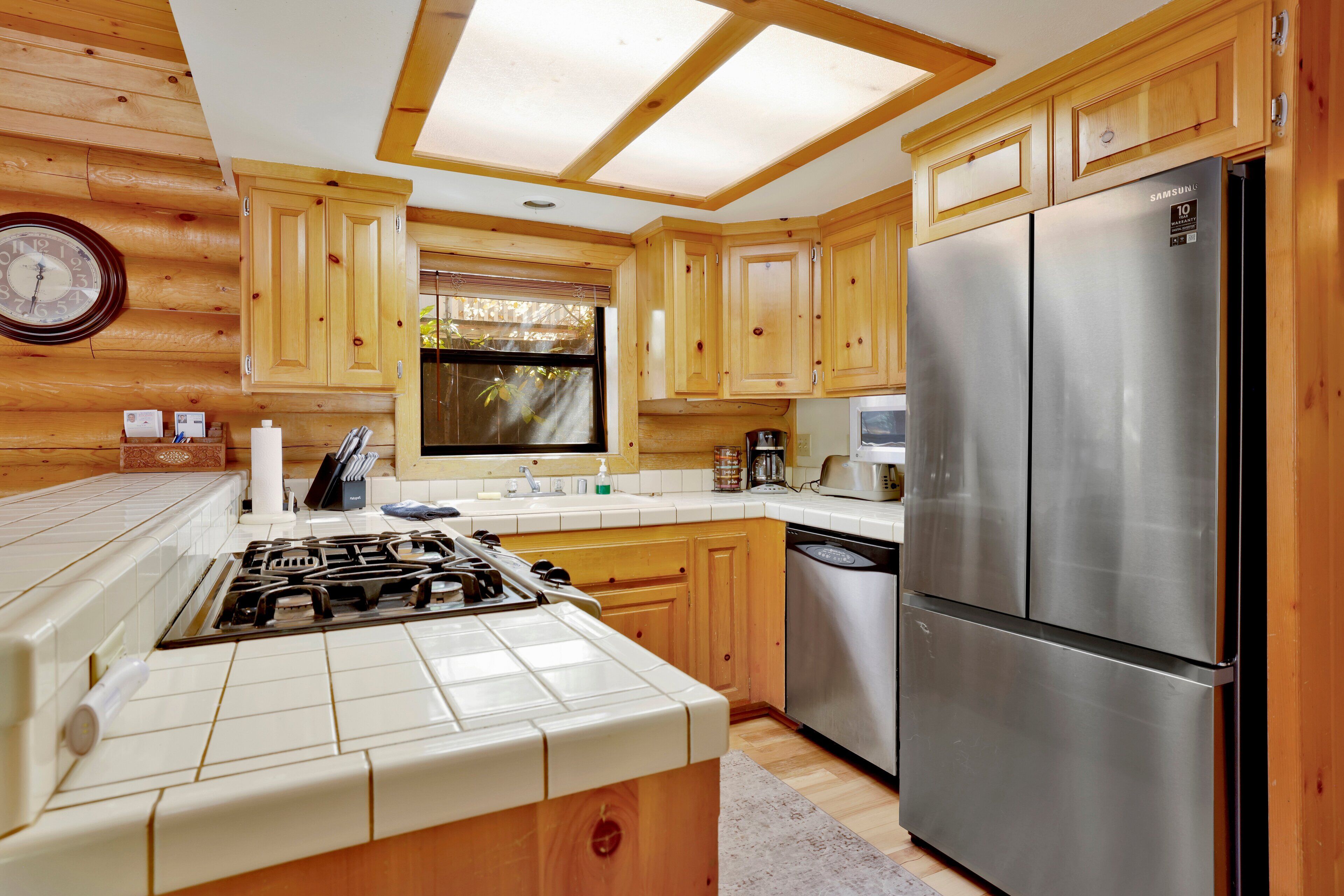A kitchen with wooden cabinets, a stainless steel refrigerator, and a gas stove.