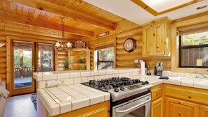 A kitchen with wooden cabinets, a gas stove, and a sink. - Knotty AND Nice #177 (Big Bear Lake)