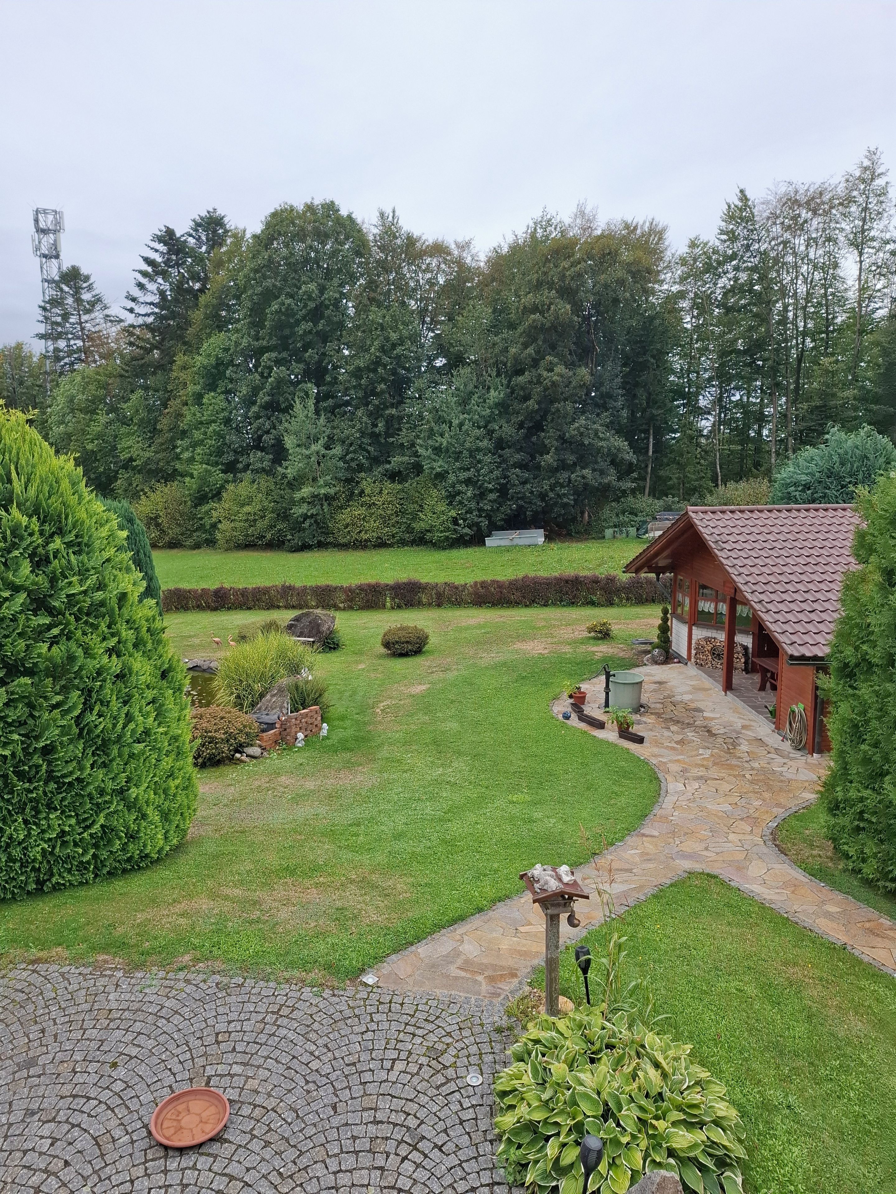 Ein gepflegter Garten mit einem gepflasterten Weg, der zu einer Holzhütte führt.
