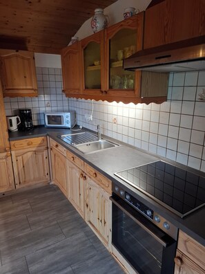 A kitchen with wooden cabinets, a microwave, a coffee maker, and a stove. - 1A Apartment TOP (Klingenbrunn)