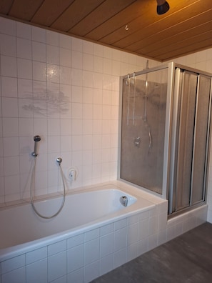 Ein Badezimmer mit Badewanne, Dusche und gefliesten Wänden.