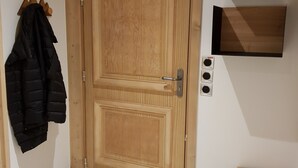 A wooden door with a handle, a coat rack with a black jacket, and three wall-mounted light switches. - Interior comfort and divine sensations outside. New MGM apartment. (Peisey-Vallandry)