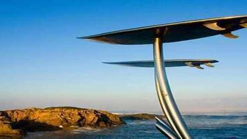 Una estructura metálica con superficie plana, posiblemente una plataforma de observación, con vistas a una costa rocosa y al océano.