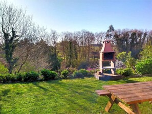 Ein Picknickbereich mit Holztisch und Grill in einem Garten.