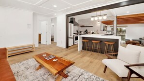 A modern kitchen with a central island, bar stools, and a dining area with a wooden table and chairs. - Vista Pines #234 (Big Bear Lake)