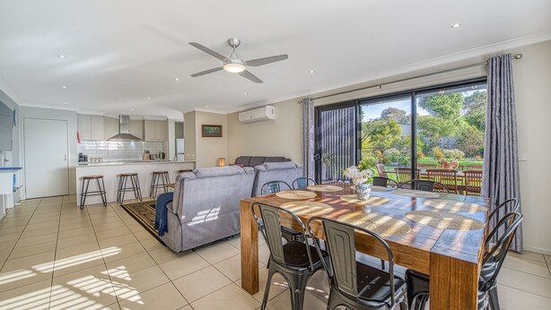 A modern kitchen with white cabinets, a grey sofa, and a dining area with a wooden table and chairs. - Seabreeze Haven - Wifi, Netflix, family and pet friendly beach house (Cowes)