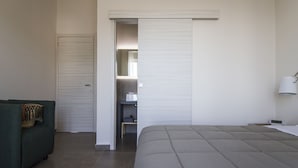 Ein Schlafzimmer mit Bett, einem grünen Sofa, einem Kleiderschrank und einem Spiegel.