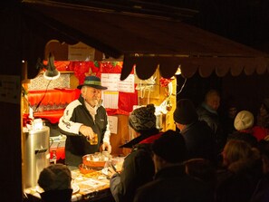 Un puesto de comida con un cartel de menú, una persona sirviendo cerveza y una multitud de gente.