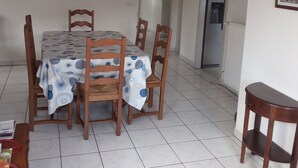 Un comedor con una mesa dispuesta para cuatro personas, rodeada de sillas de madera, un candelabro y cuadros enmarcados en las paredes.