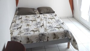 Un dormitorio con cama, ventana con persianas, candelabro y viga de madera.
