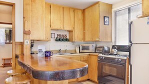 Une cuisine avec des meubles de rangement en bois, un four à micro-ondes, une cuisinière et un réfrigérateur.