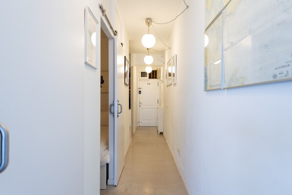A narrow hallway with white walls, a door at the end, and a map on the right wall.