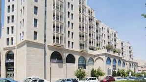 A multi-story hotel with a stone facade, multiple balconies, and a parking lot with various cars. - ❤MAMILLA 2 bdrs w. view ❤ My BEST JLM Experience ❤ (Jerusalem)