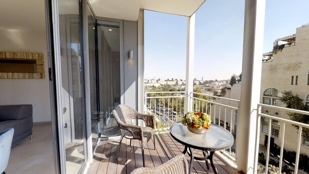 A balcony with wicker furniture, a glass door, and a view of the cityscape. - ❤MAMILLA 2 bdrs w. view ❤ My BEST JLM Experience ❤ (Jerusalem)