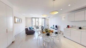 A modern kitchen with white cabinets, a dining table with chairs, and a large window providing natural light. - ❤MAMILLA 2 bdrs w. view ❤ My BEST JLM Experience ❤ (Jerusalem)